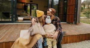 Eine Familie sitzt auf der Terrasse vor einem Passivhaus